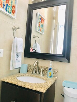 Une salle de bain équipée d’un lavabo, d’un miroir, d’un porte-serviettes et d’un panneau indiquant « INTERDICTION DE FUMER ».