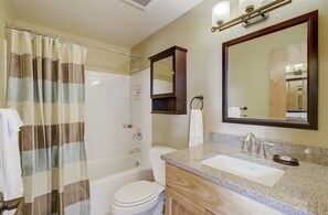 Un baño con ducha, inodoro, lavabo y espejo.