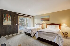 Una habitación de hotel con dos camas, un ventanal grande y un cuadro en la pared.