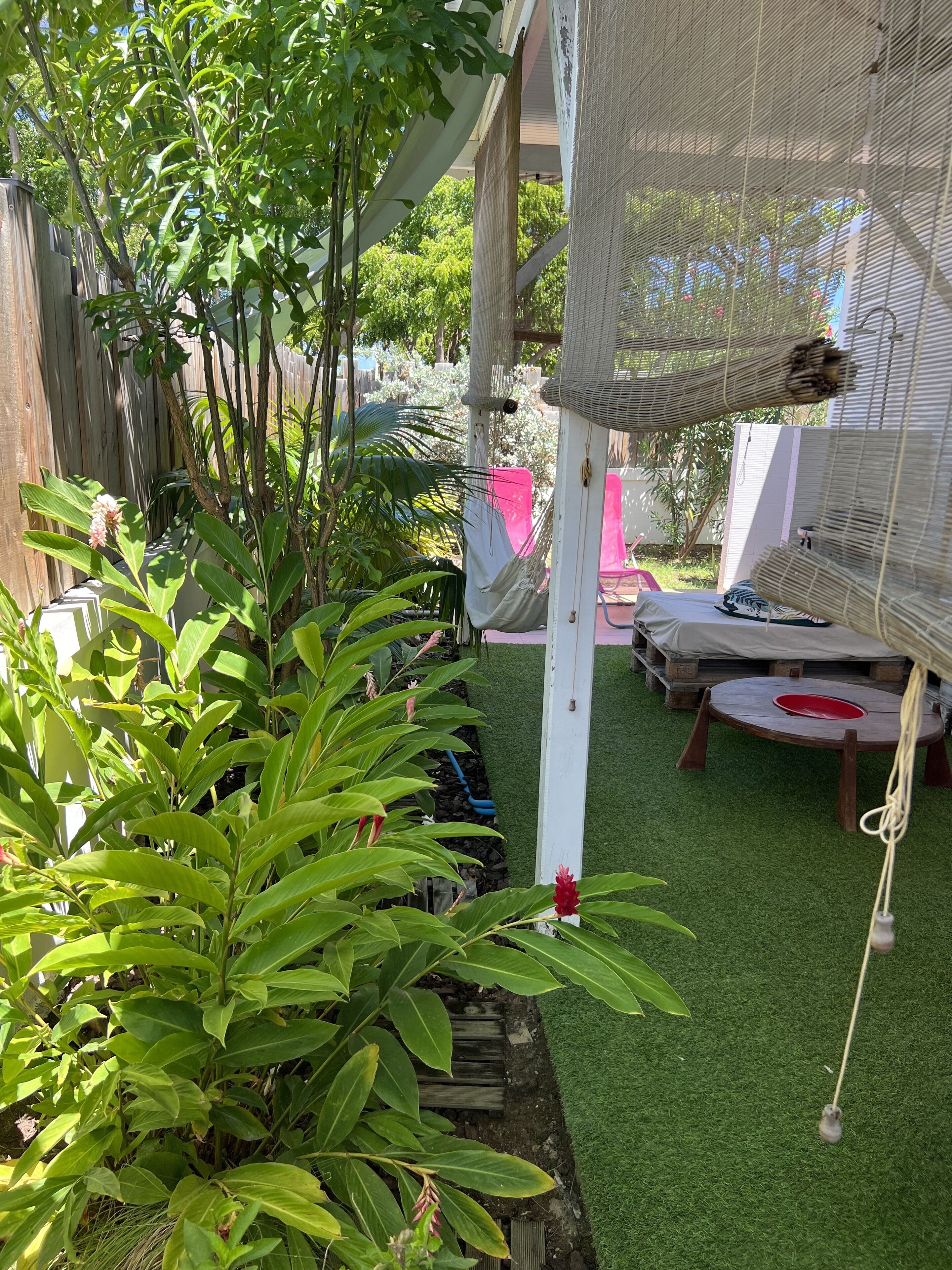 A covered outdoor area with artificial grass, a hammock, and a small table with a red bowl.