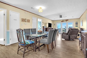 A dining area with a glass table, chairs, and a brown leather sofa.