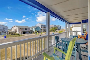 A covered porch with a view of houses and a road.