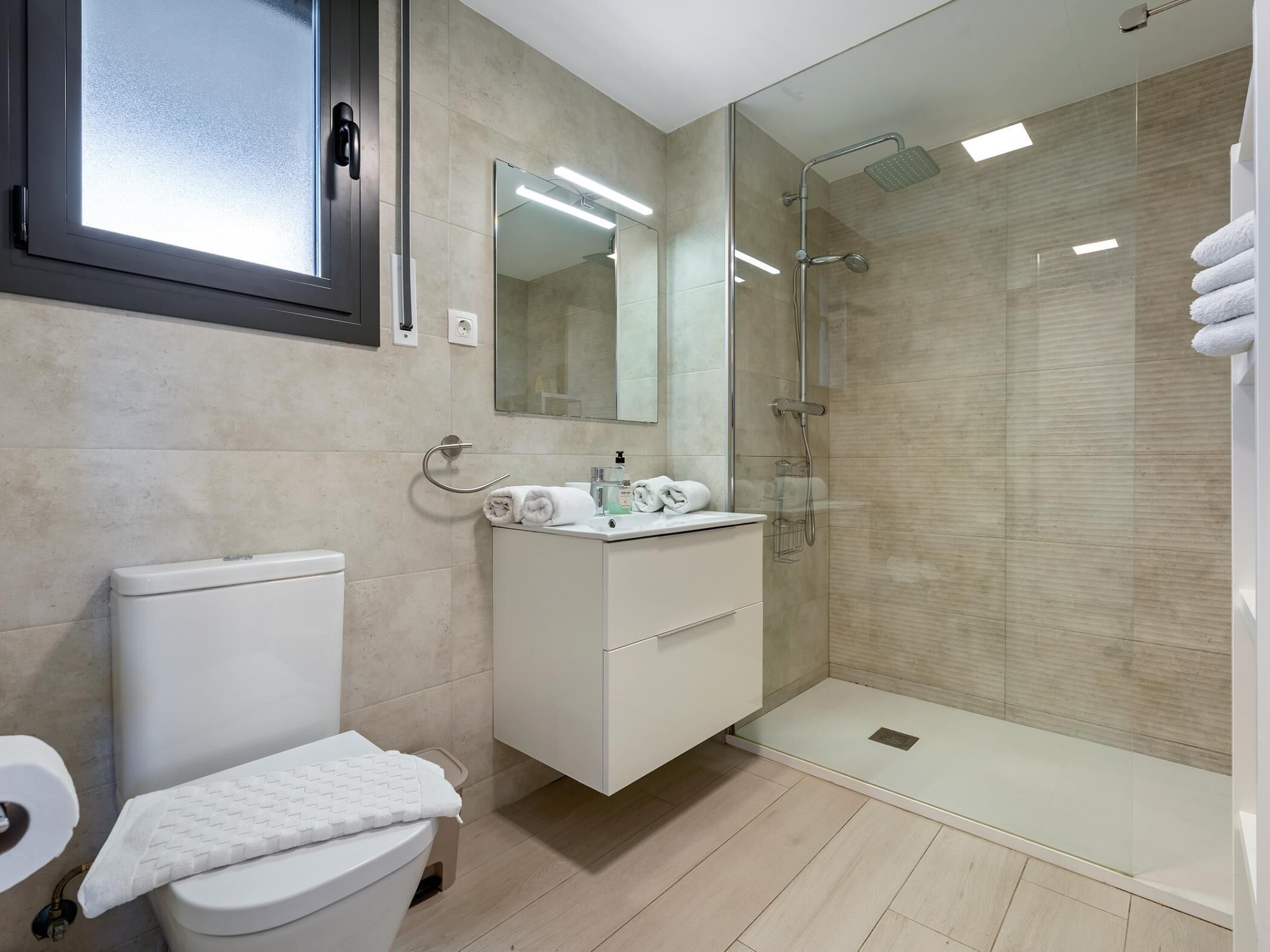 Un bagno moderno con toilette, lavabo e cabina doccia in vetro.