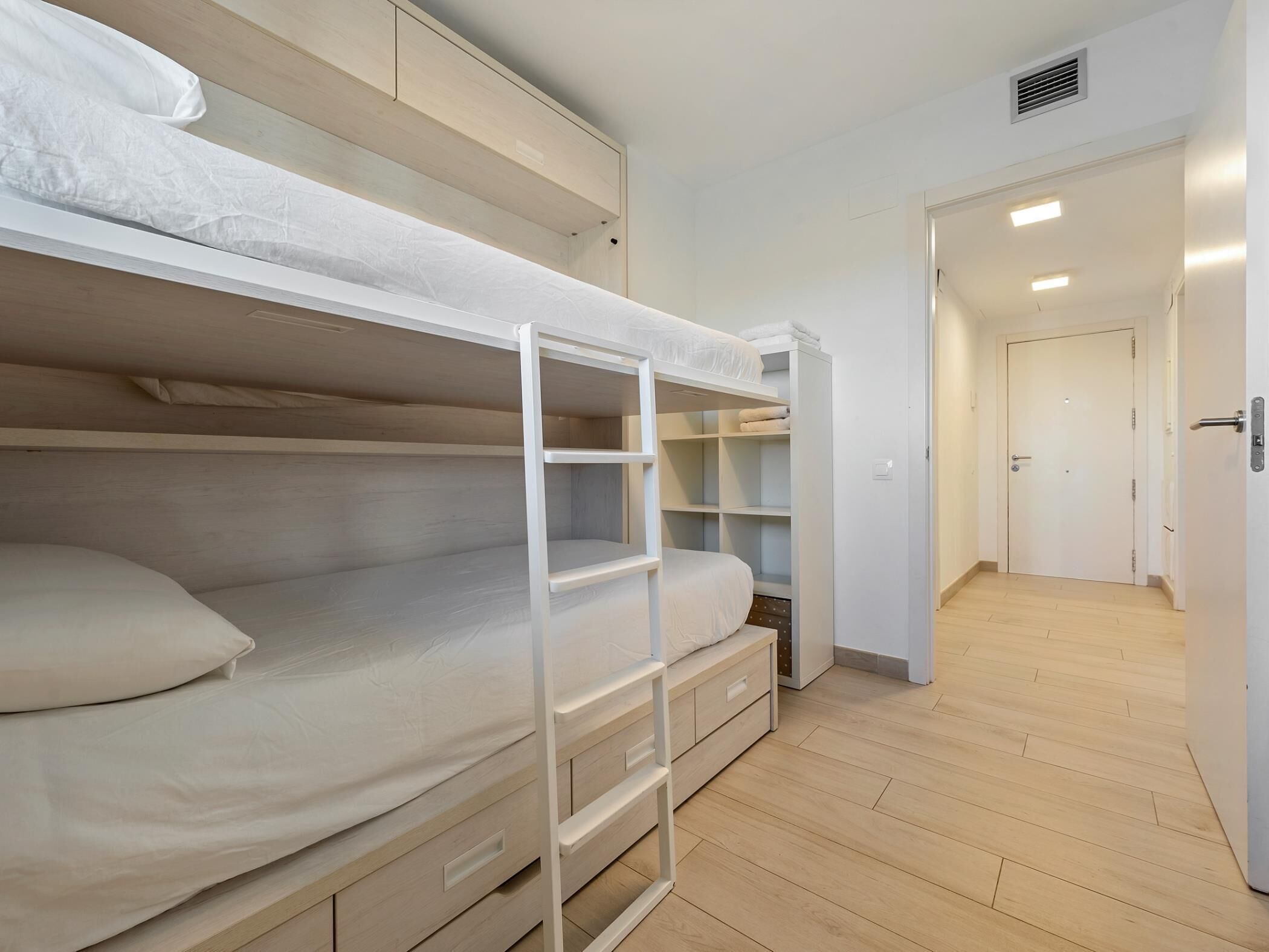 Ein Schlafzimmer mit Etagenbetten, integriertem Schreibtisch und Regalen.