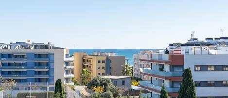 Un paisaje urbano costero con edificios modernos, cielo despejado y vista al mar.