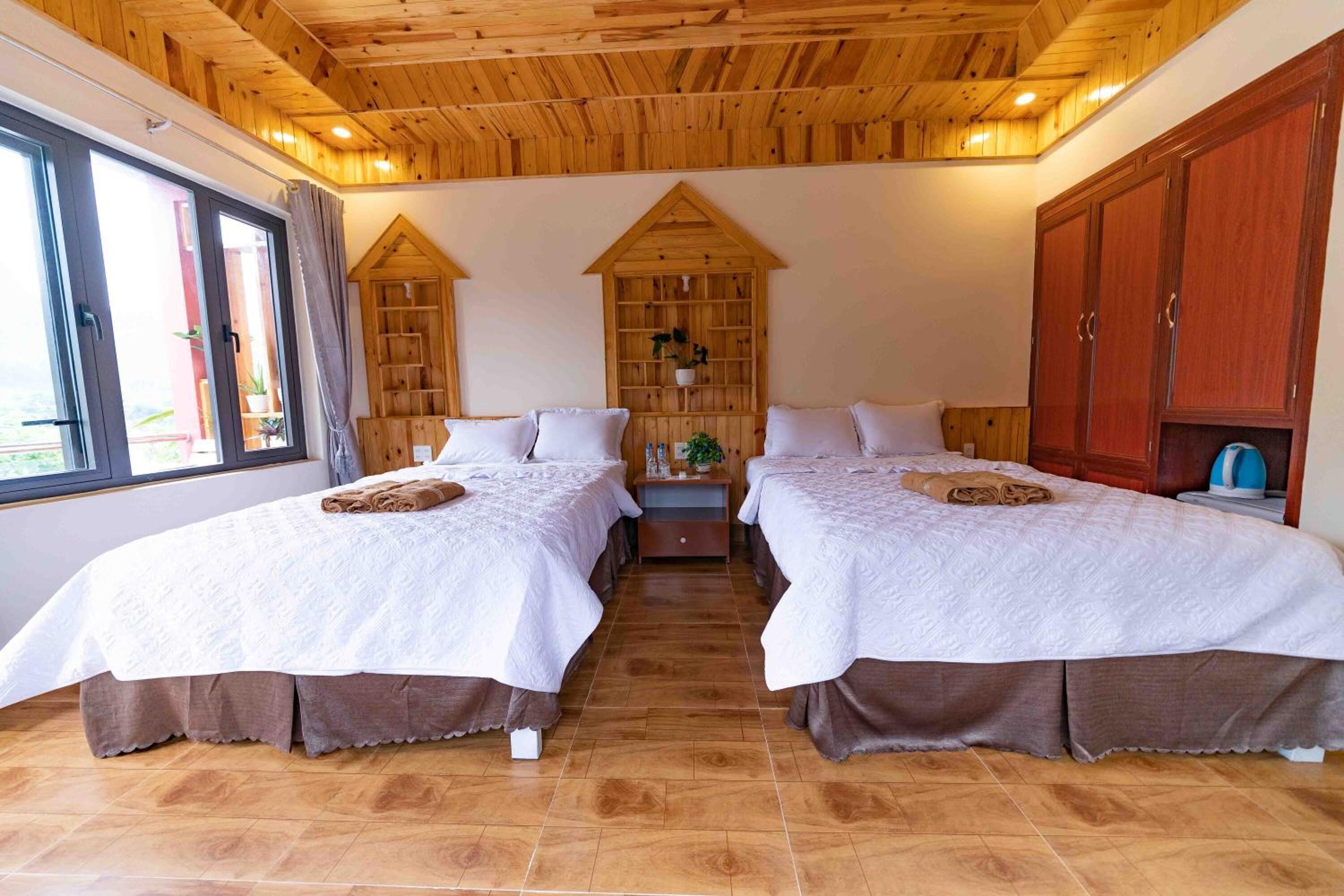 Ein Zimmer mit zwei Betten, Holzboden, großen Fenstern und einer festen Bibliothek.