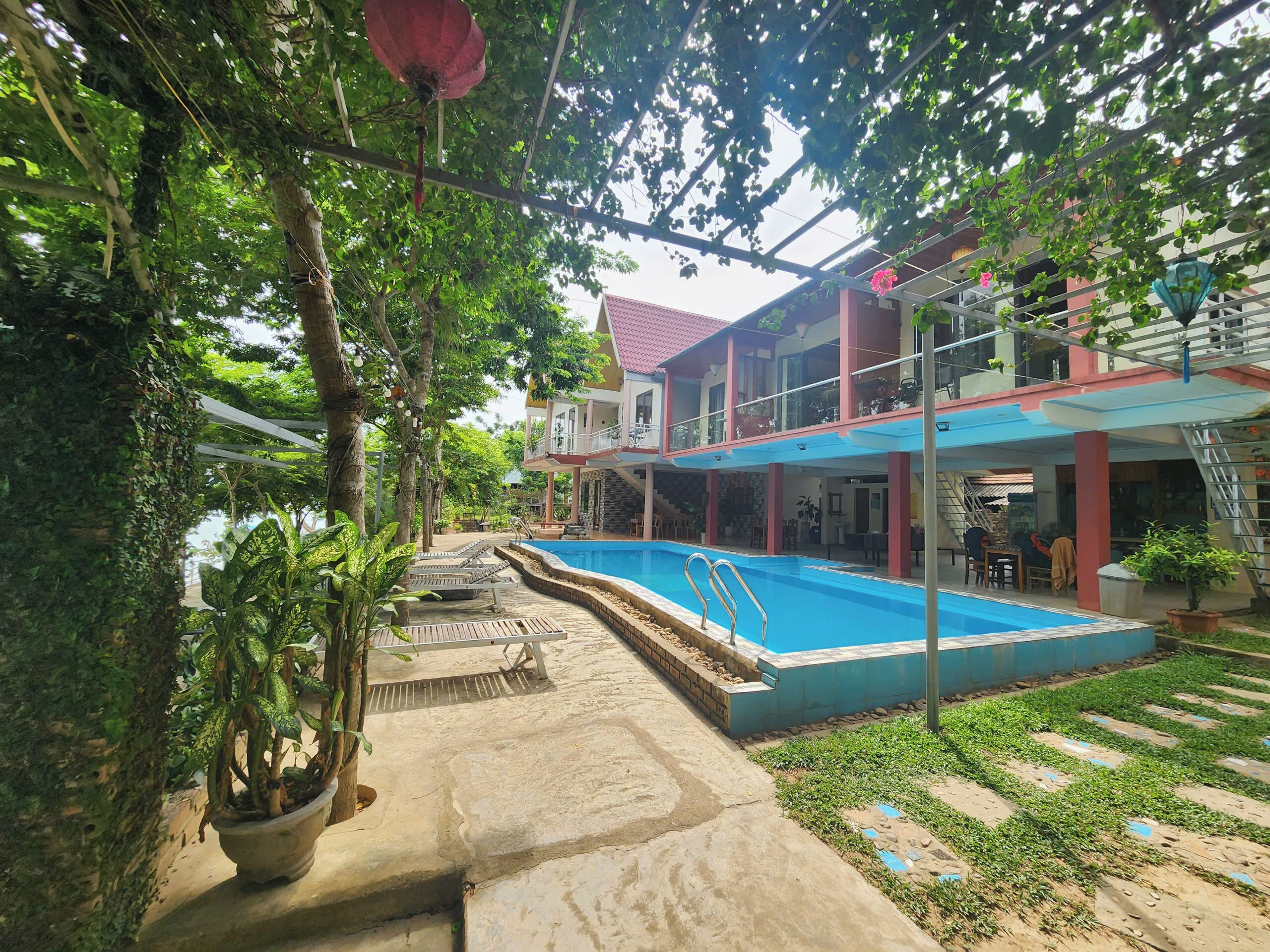 A residential area with a swimming pool, potted plants, and a two-story house with balconies.