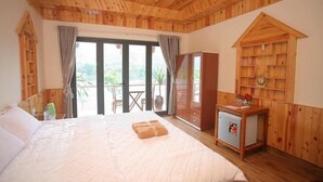 A wooden-paneled bedroom with a bed, a small refrigerator, and a wooden cabinet. - Restful River Bungalow (Phong Nha)