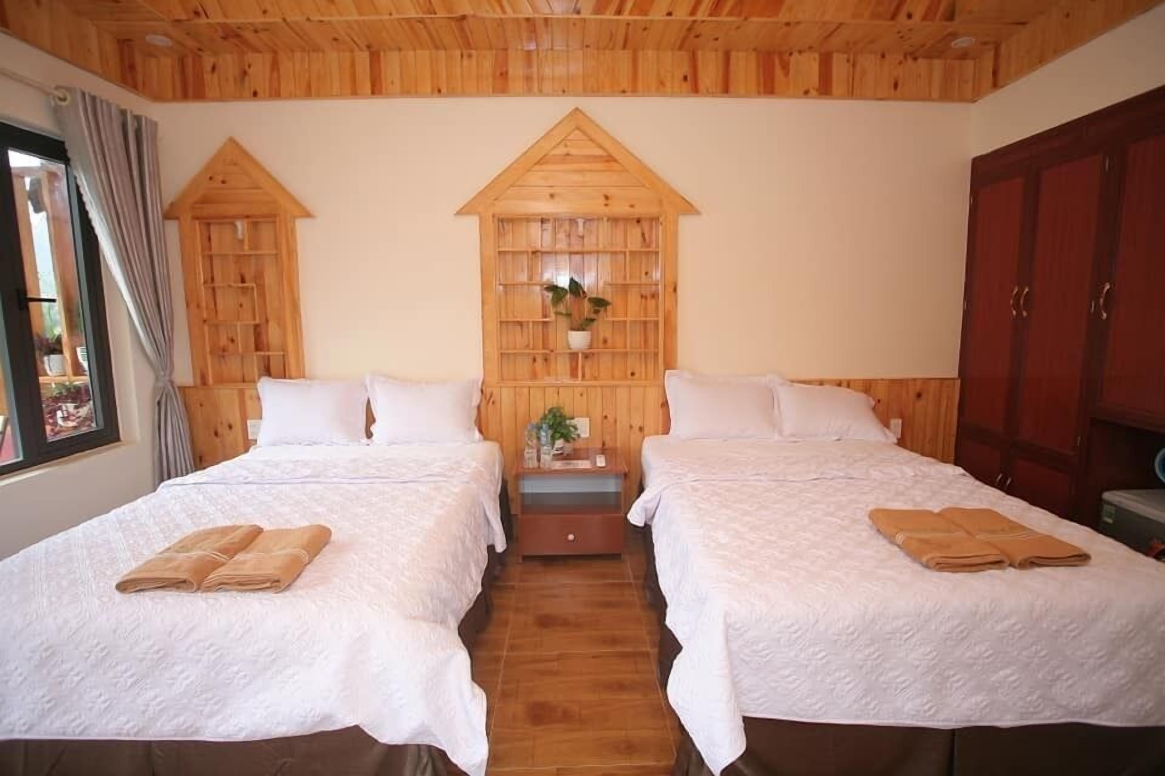Una habitación con dos camas, cabeceros de madera, un estante con una planta y un armario.