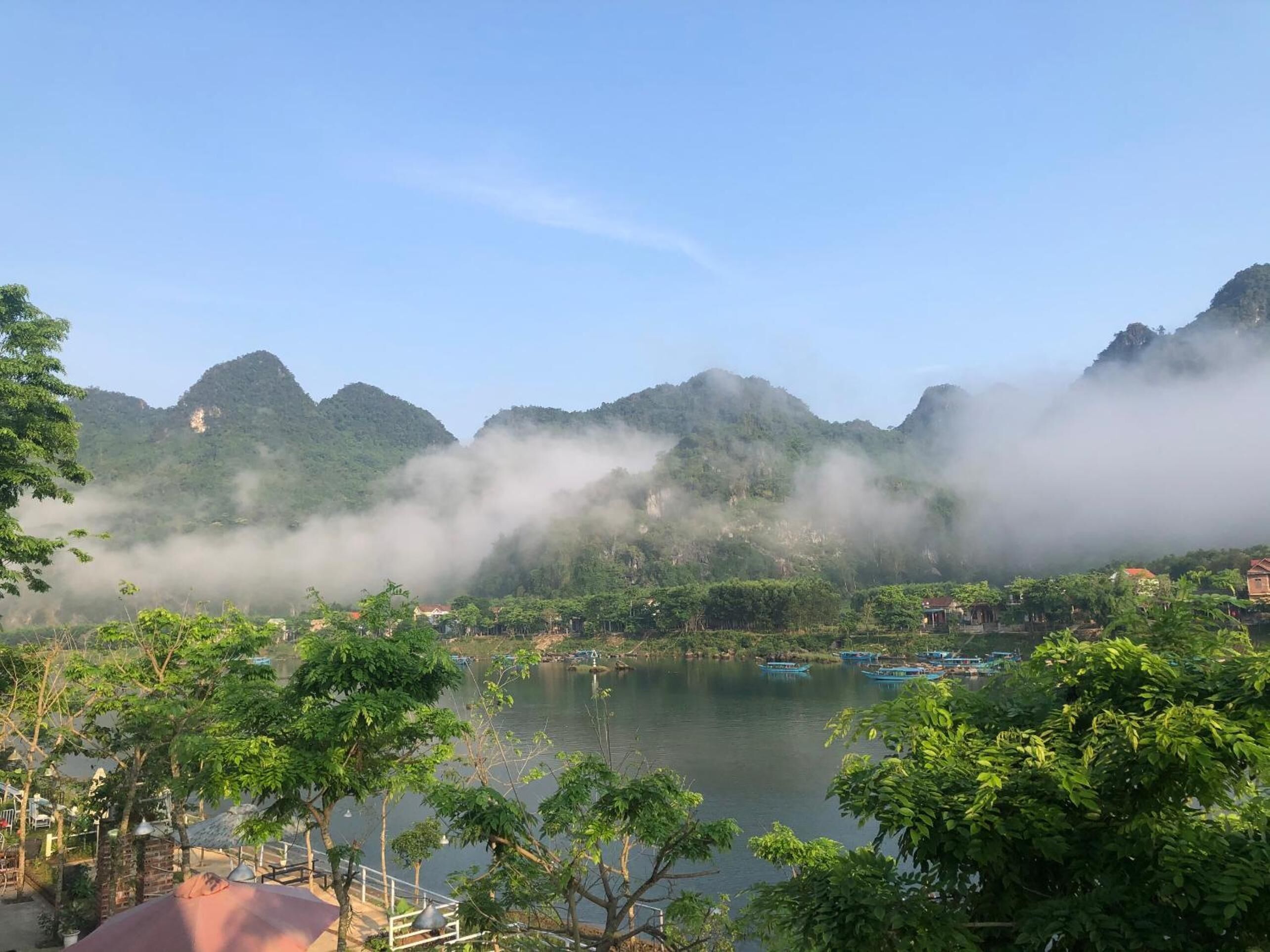 A serene lakeside view with mountains in the background and a clear sky.