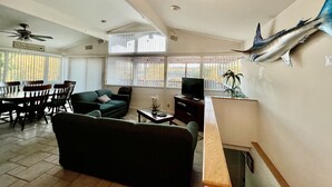 Un salon comprenant un canapé, un téléviseur et un coin repas avec des chaises et une table.