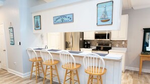 A kitchen with a central island, white bar stools, and a sign indicating 'DESTIN, FL'.