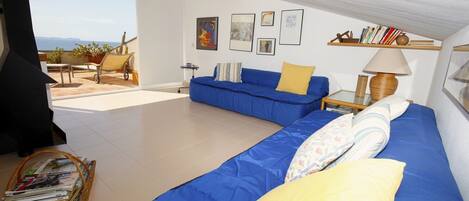 Una sala de estar moderna con un sofá azul, un cojín amarillo y una cesta de mimbre para revistas.