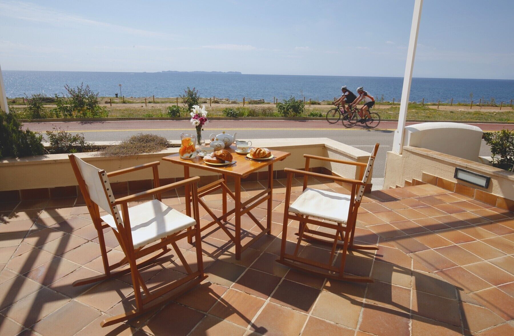 A patio with a table set for two, overlooking a coastal view.
