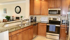 Una cucina moderna con mobili in legno, elettrodomestici in acciaio inossidabile e un piano di lavoro in granito.