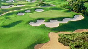 Un campo da golf con bunker, un club house e edifici residenziali sullo sfondo.
