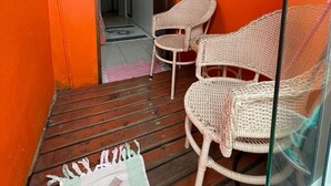 A small room with two wicker chairs, a wooden floor, and an orange wall. - Pousada Veromar (Paraty)