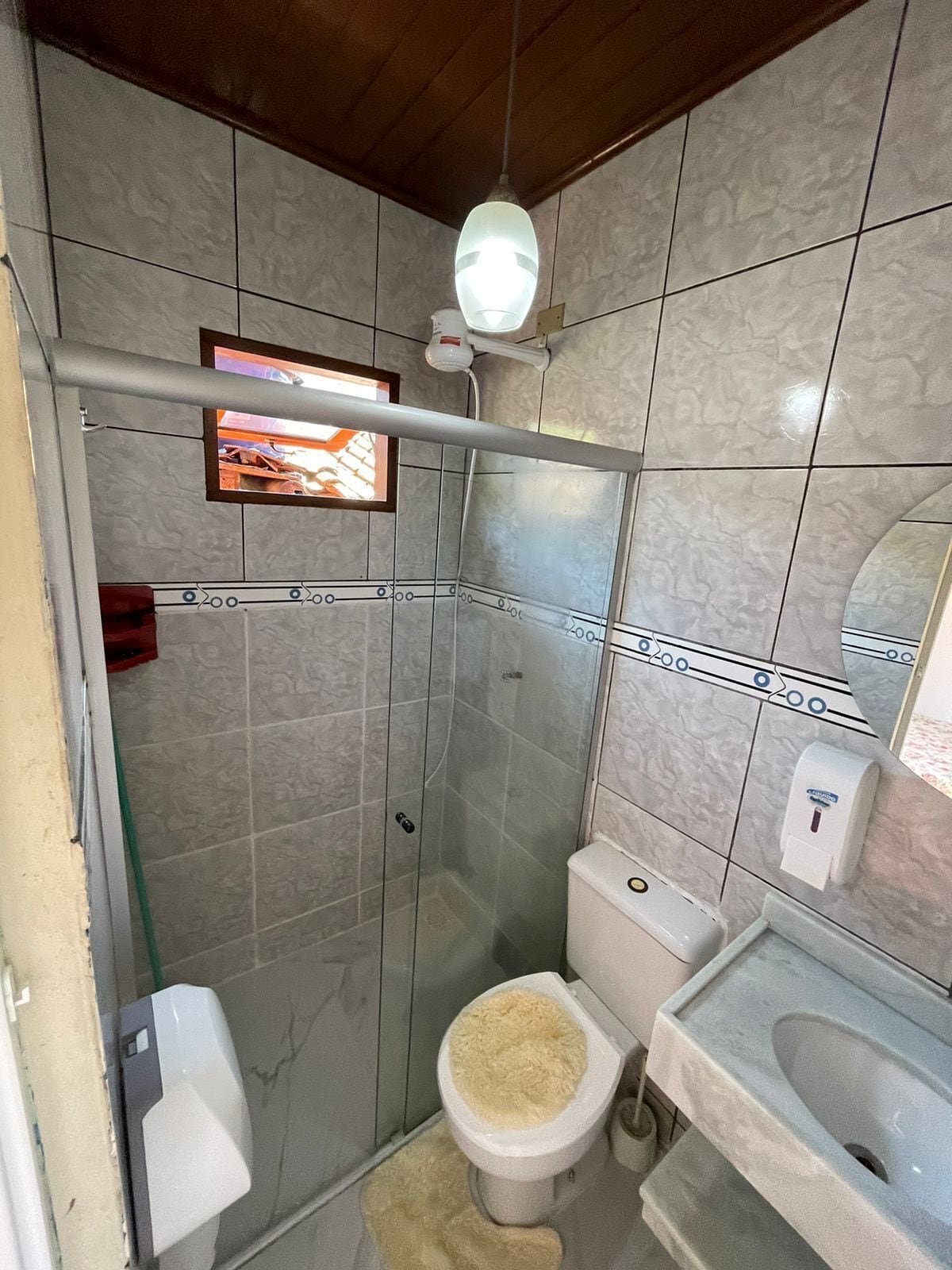 Un baño con ducha, inodoro, lavamanos y secador de manos.