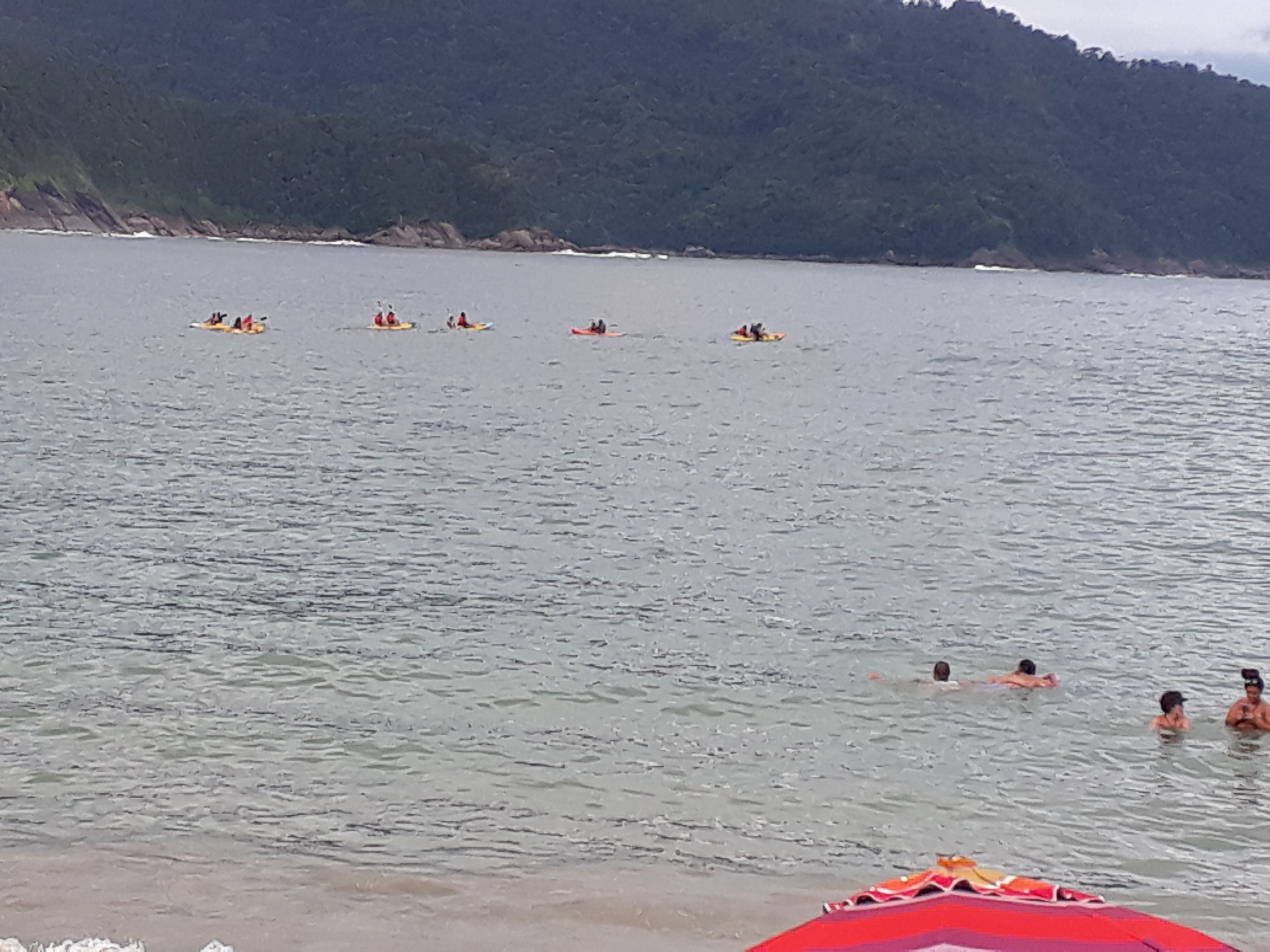 A beach with people in the water and on surfboards.