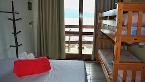 A room with a bunk bed, a bed with a red pillow, and a coat rack. - Pousada Veromar (Paraty)