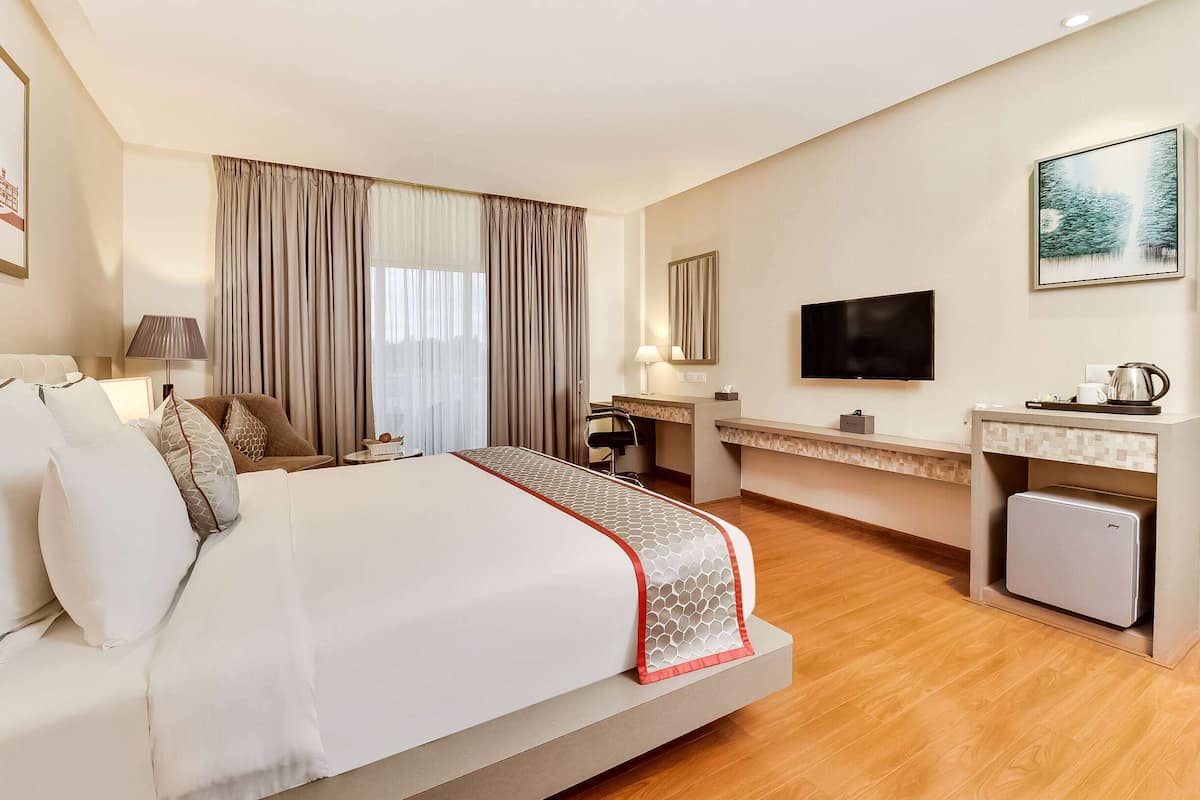 Ein Hotelzimmer mit Bett, Schreibtisch, Fernseher und kleinem Kühlschrank.