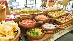 Een buffet met verschillende gerechten, waaronder plakjes tomaat, groene bonen en andere soorten.