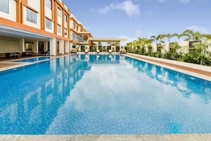 Un hôtel moderne doté d’une grande piscine, d’un espace extérieur aménagé et d’une végétation luxuriante.