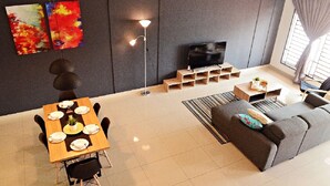 Un salón moderno con sofá, televisor y una mesa de comedor dispuesta con platos y una planta.