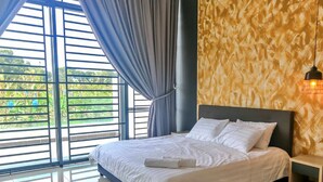 Habitación de hotel con una cama grande, una mesita de noche y vistas a través de una ventana con cortinas.
