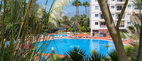 Uma área de piscina com espreguiçadeiras e palmeiras.