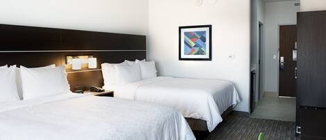 A hotel room with two beds, a nightstand, a framed picture on the wall, and a wardrobe.