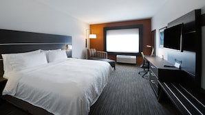 Habitación de hotel con una cama grande, un escritorio con computadora, un televisor y una ventana con vistas.
