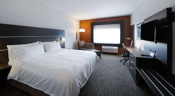 Habitación de hotel con una cama grande, un escritorio con computadora, un televisor y una ventana con vistas.