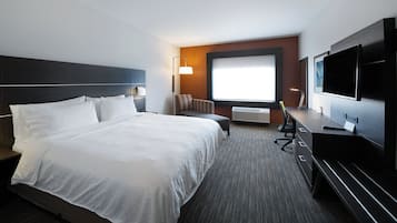 Habitación de hotel con una cama grande, un escritorio con computadora, un televisor y una ventana con vistas.