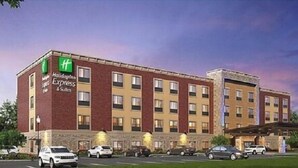 Un hotel Holiday Inn Express con fachada de ladrillo, múltiples ventanas y un estacionamiento con varios coches.