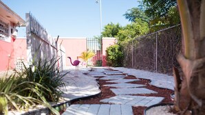 A pathway with stepping stones leading to a fenced area with a flamingo. - COCOPLUM REST N HIDEAWAY #2 (Bahamas)