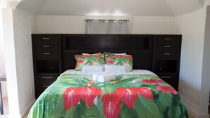 A neatly made bed with a floral bedspread, a dark headboard, and a small bedside table with a lamp. - COCOPLUM REST N HIDEAWAY #2 (Bahamas)
