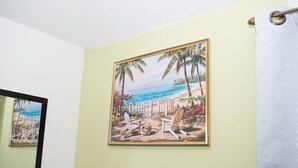 A framed painting of a beach scene with palm trees and a pathway leading to beach chairs. - COCOPLUM REST N HIDEAWAY #2 (Bahamas)