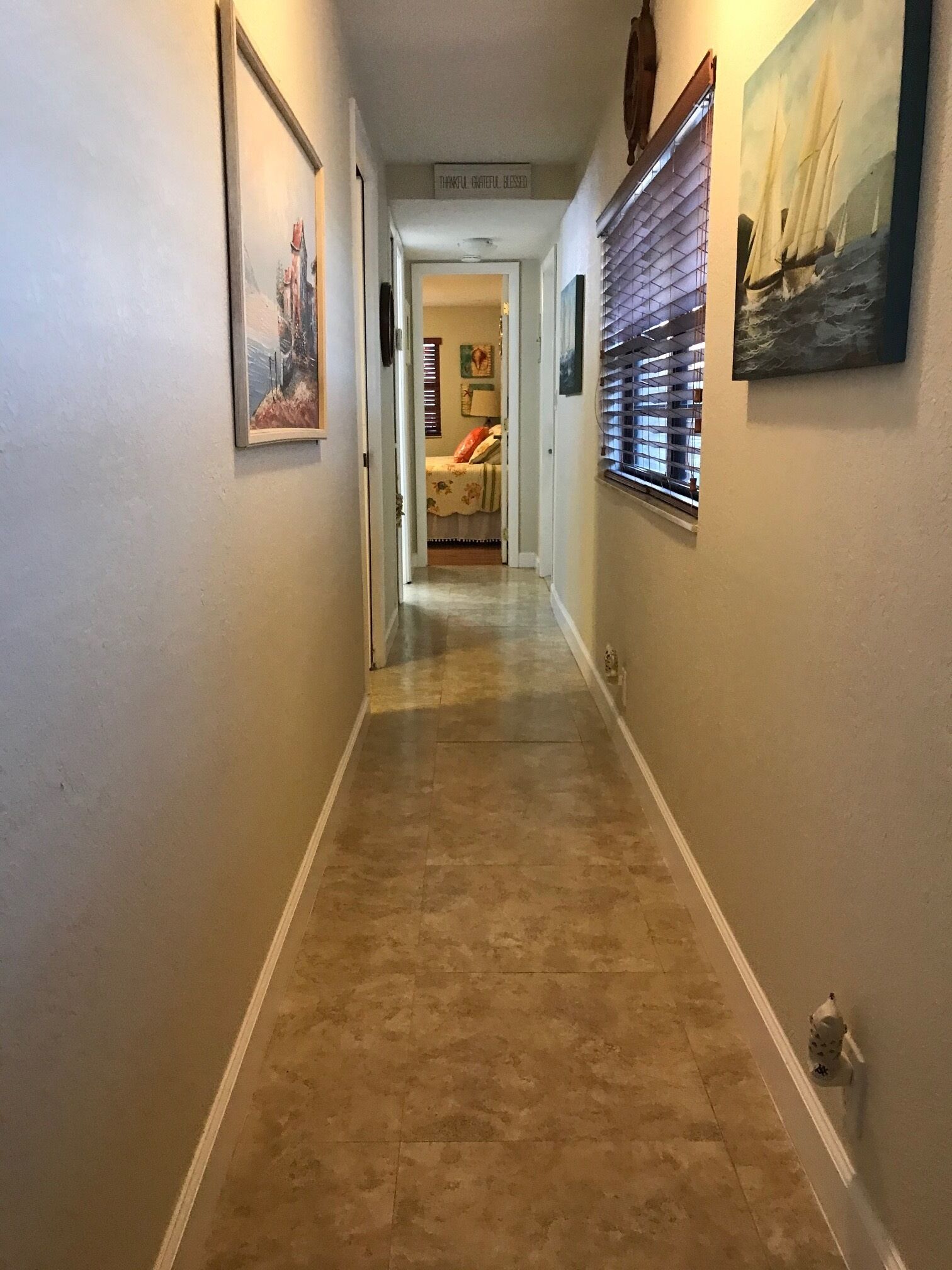 A hallway with a tiled floor, a door at the end, and a sign above it.