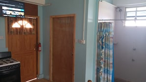 Une pièce avec une porte en bois, un réchaud à gaz, un rideau et une fenêtre.
