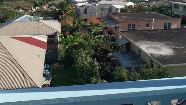 Un quartier résidentiel avec des maisons, une vue sur l’océan et des collines en arrière-plan.
