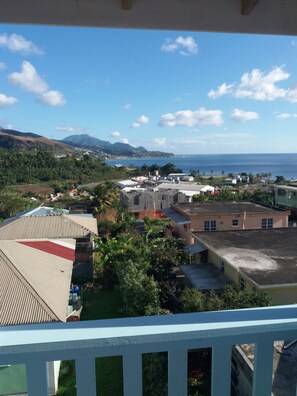A residential area with houses, a view of the ocean, and hills in the background. - Suite Pepper (Mahaut)