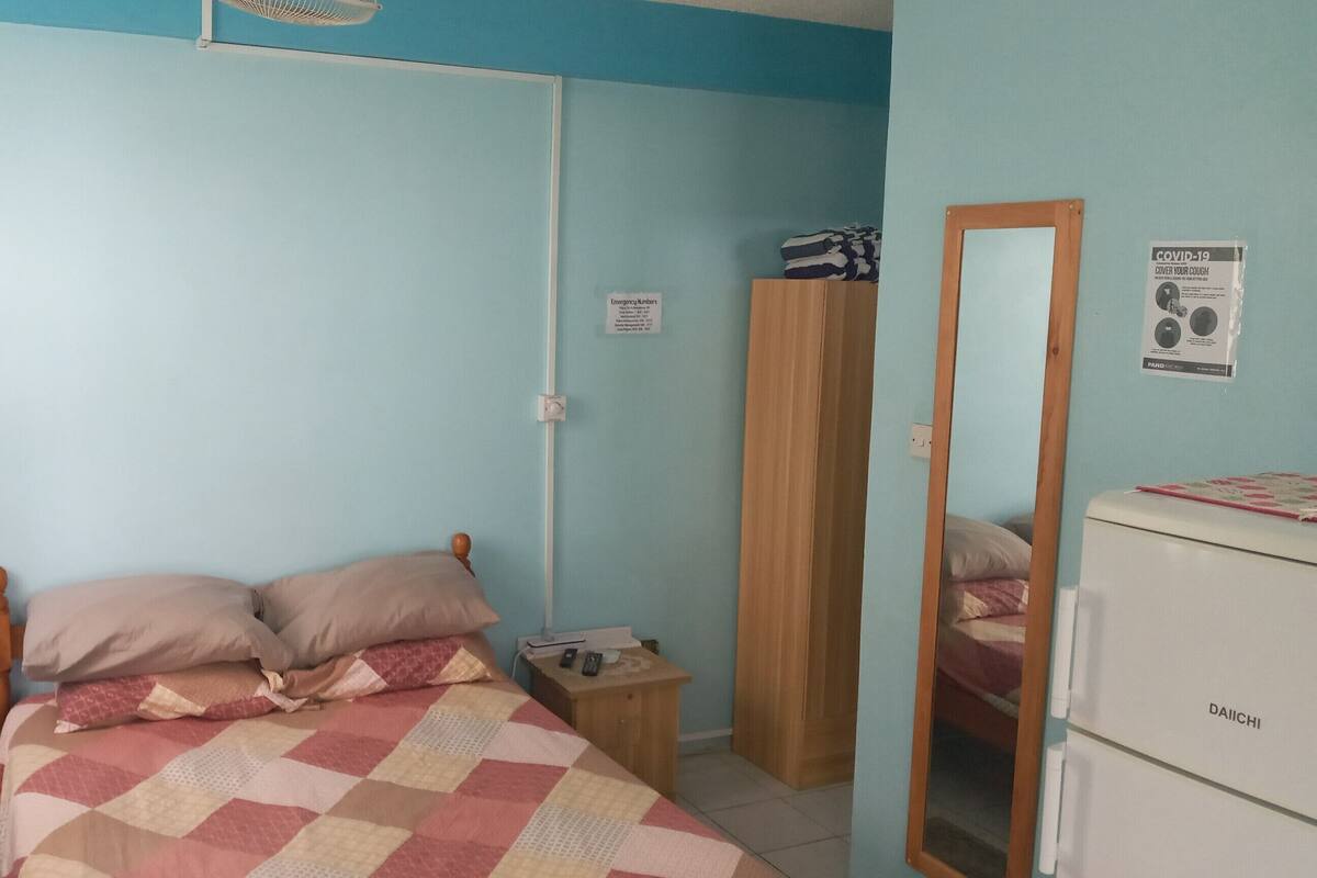 Ein Schlafzimmer mit einem Bett, einem Nachttisch, einem Spiegel und einem Kleiderschrank.