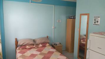 A bedroom with a bed, a nightstand, a mirror, and a wardrobe.