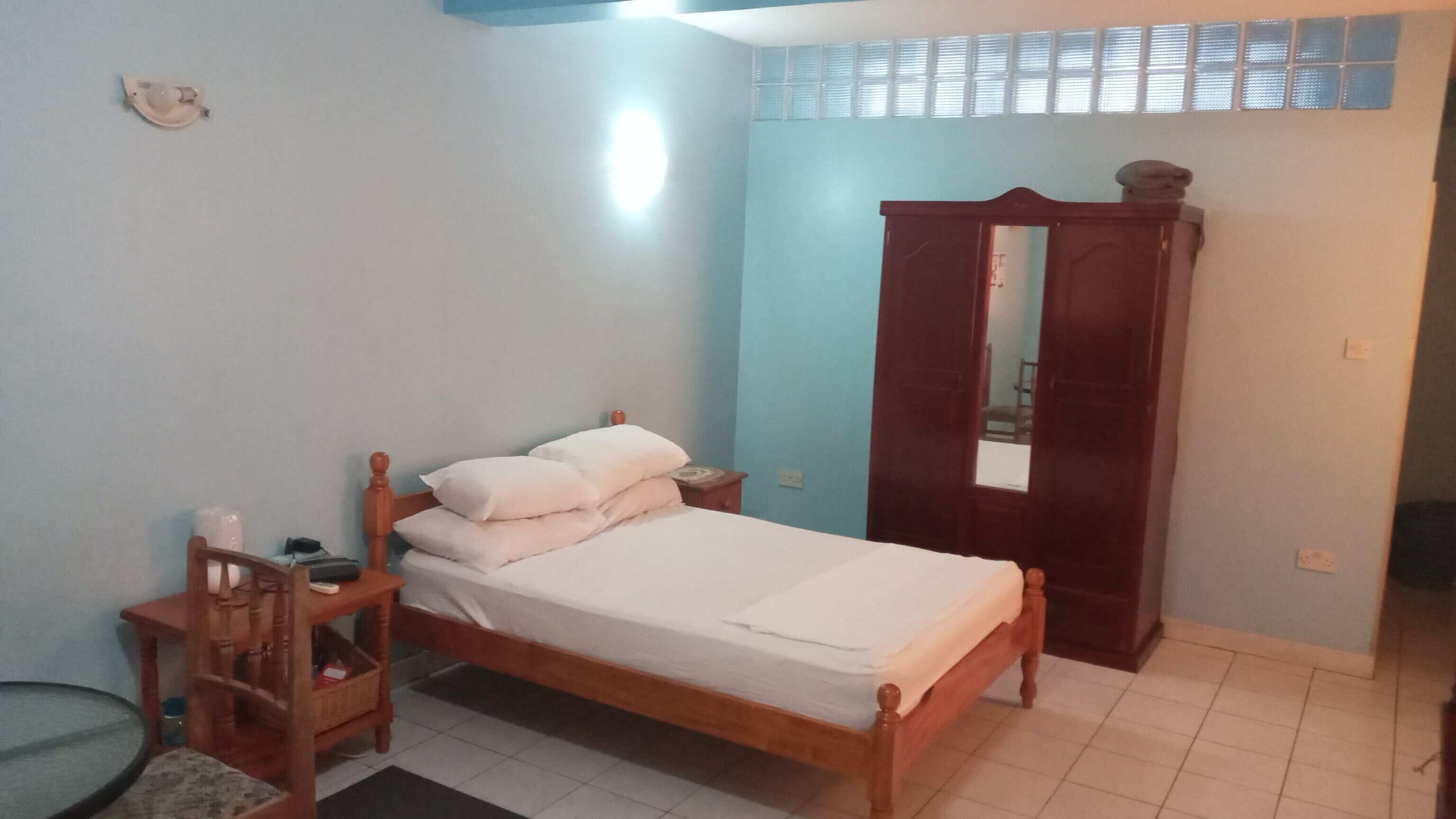 A bedroom with a wooden bed, a nightstand, a small table, and a wardrobe with a mirror.
