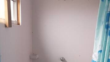 A small, enclosed shower area with a stone-tiled floor, a white sink, and a blue curtain.