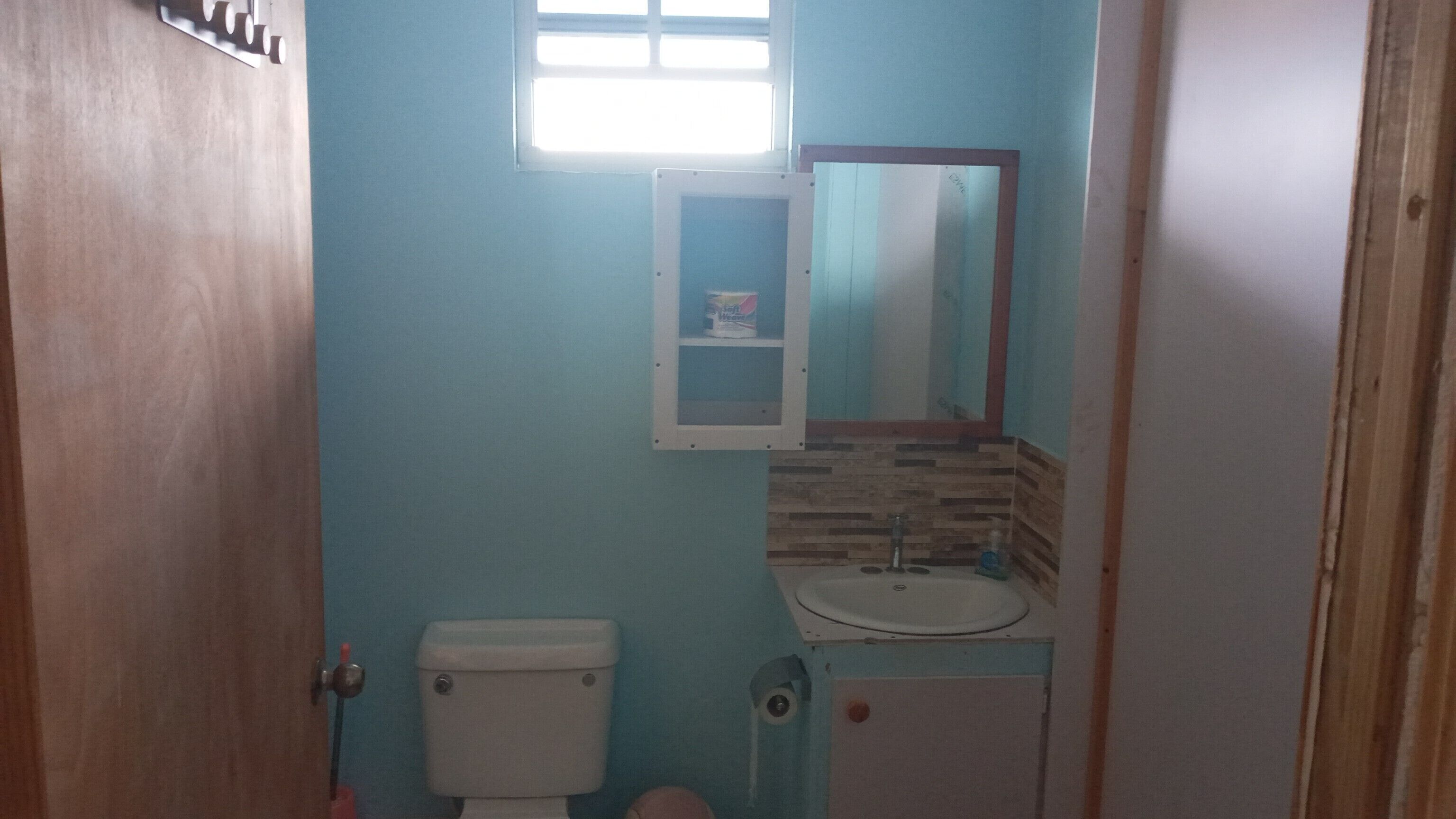 Un baño pequeño con inodoro, lavamanos y espejo.
