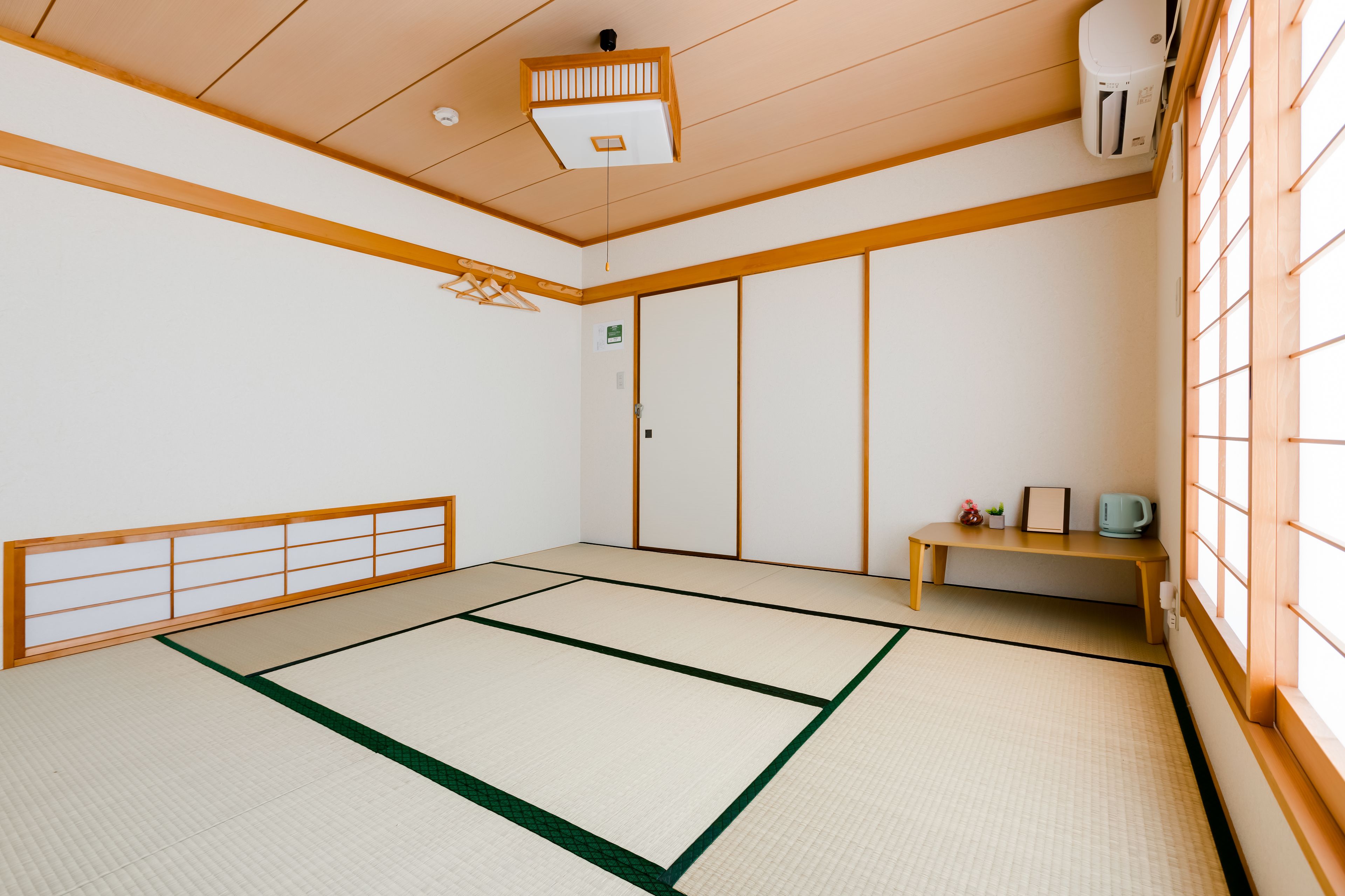 A tatami mat room with a sliding door, a small table with a cup, and a heater on the wall.