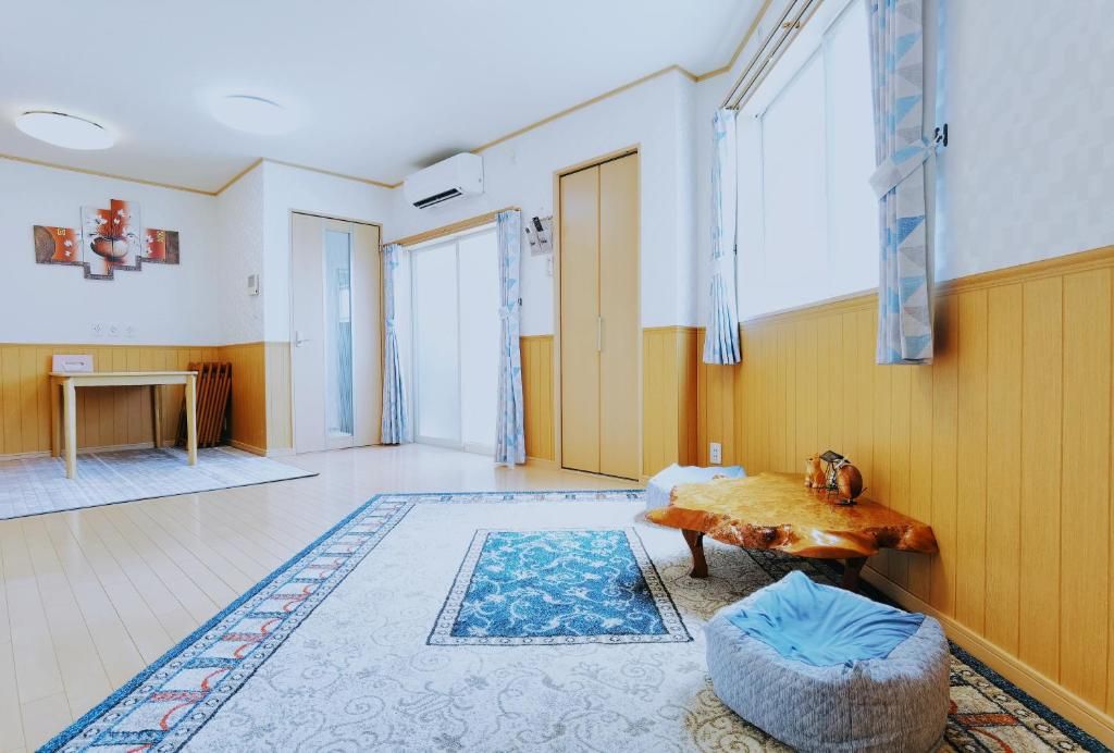 Une pièce avec un plancher en bois, un tapis à motifs bleus, un banc en bois et une petite table avec une bouilloire.
