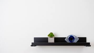 A black shelf with a small potted plant and a blue object against a white wall.